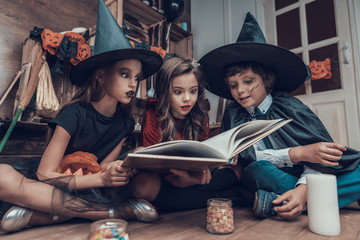 Little Children in Halloween Costumes Reading Book