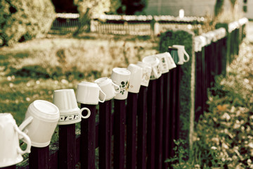 Mugs hanging on the wooden fence, vintage toned picture.