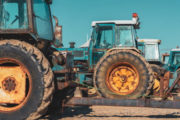 A row of blue tractors with large yellow wheels parked alongside the beach at Hornsea, East Yorkshire, UK