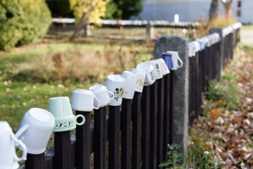 Mugs hanging on the wooden fence.