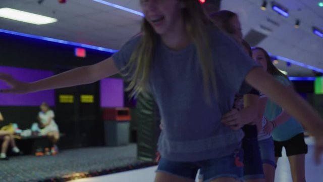 Slow motion shot of girls holding waists skating in a row / Orem, Utah, United States