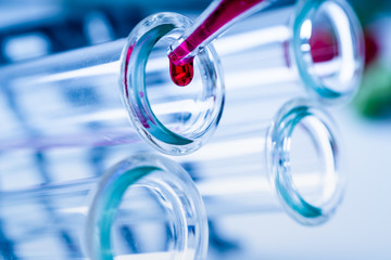 Pipette adding fluid to one of several test tubes .medical glassware.