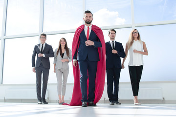 businessman-superhero and business team standing in the office.