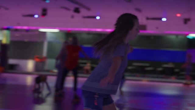 Slow motion tracking shot of girl skating and dancing to music in roller skating rink / Orem, Utah, United States