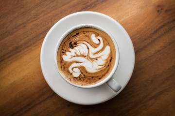 Overhead view of coffee cup with latte art on table