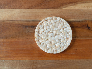 Obraz na płótnie Canvas Top view of a single multigrain rice cake on a wood cutting board at an angle.