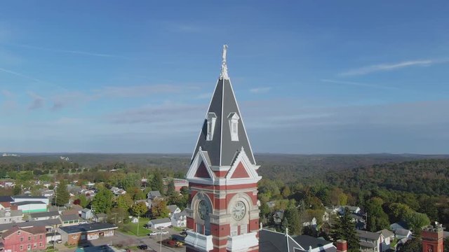 A morning orbiting aerial establishing shot of the Clarion County Courthouse steeple in the early Autumn. The Main Street business district in the distance.  	