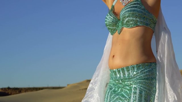 Oriental beauty dancing belly dance. Delightful and alluring grace of movements. Girl dancing in the desert. She is unrecognizable. Close-ups