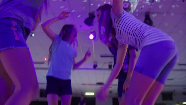 Girls dancing and singing in circle at roller skating rink under disco ball / Orem, Utah, United States