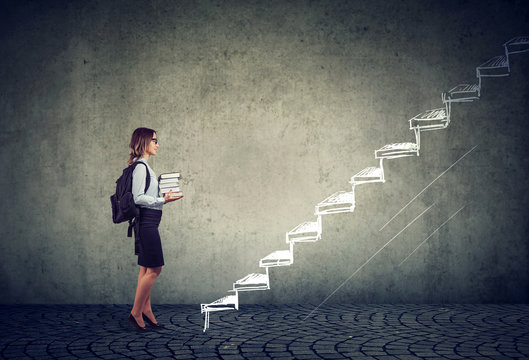 student with books standing on the stairs of education leading to success