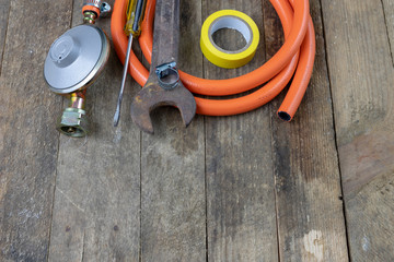 Regulator for propane-butane gas cylinder and accessories on a wooden workshop table. Gas accessories in the workshop.