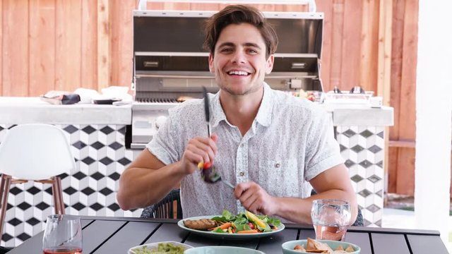 Young white man sitting at a table in the garden