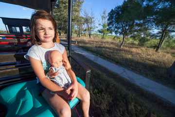 Obraz premium Child girl with doll at Mini-train of Barril Beach