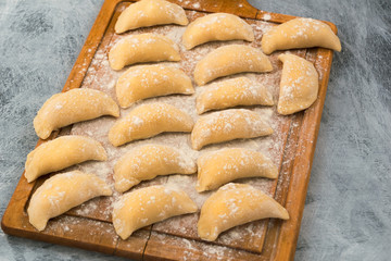 Hand-made dumplings with filling, laid on a kitchen cutting Board.