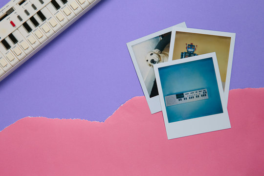 Polaroid photo of a keyboard on pink and violet ripped edge paper with the keyboard visible in the corner