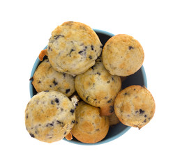 Top view of freshly baked bite size blueberry muffins in a blue bowl isolated on a white background.