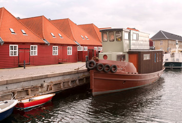 Fototapeta na wymiar Red roofs houses near river bay with moored boats in Copenhagen, Denmark. City with water chanels