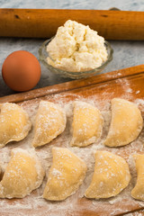 Fototapeta na wymiar Homemade dumplings of dough stuffed with cottage cheese, chicken egg, cutting Board.