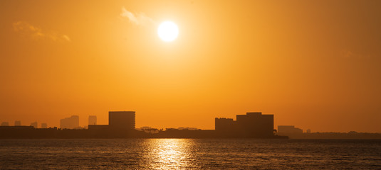 Sunrise over city buildings across the ocean