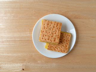 Top view of two freshly baked lemon squares on a white plate atop a wood table.