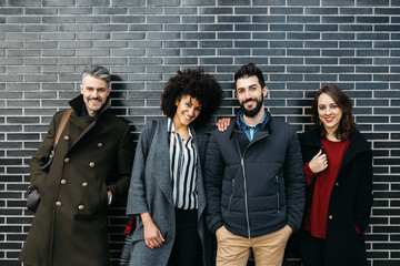 Happy casual friends over black brick wall.