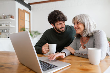 Mother and her son using laptop at home.