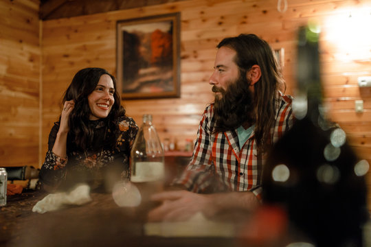 Two friends smile and talk together in a cabin in upstate New York