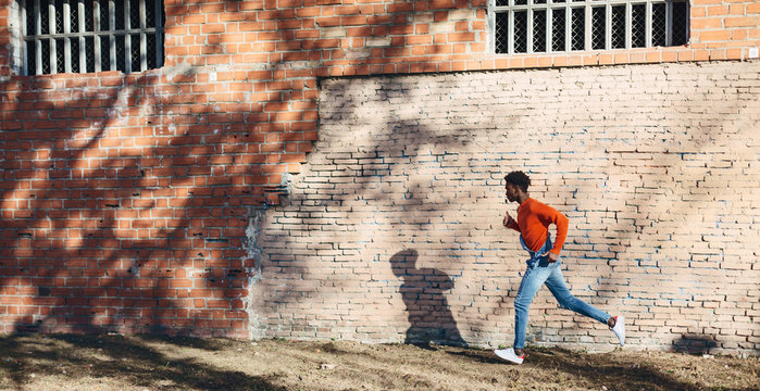 Portrait of a cool black man running on the street.