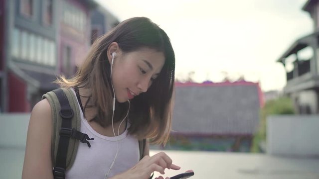 Asian backpacker blogger woman using smartphone for chat, check social media and listen to music while traveling at Chinatown in Beijing, China. Lifestyle backpack tourist travel holiday concept.