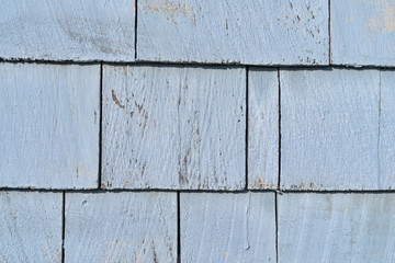 Close view of cedar shingles with fading blue paint.