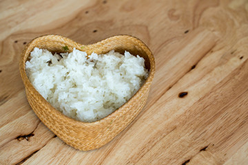 Streamed sticky rice in wicker basket isolated on wooden table background. It is Thai's favorite menu which is widely spread across the country, especially having it with spicy menu. It is inevitable.
