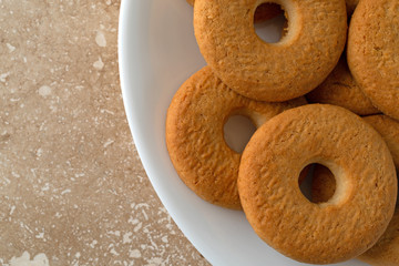 Top close view of coconut cookies on a white plate atop a marble counter top.