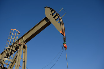 Oil and gas production, crude oil pump jack against a clear blue sky, in the Powder River Basin. 