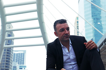 Businessman sitting on walking street and smile portrait.