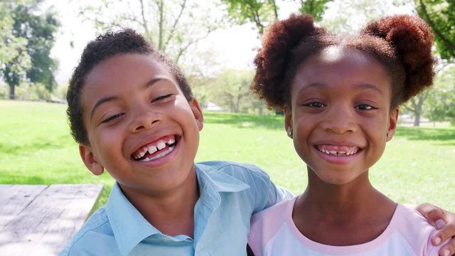 Slow Motion Portrait Of Smiling Brother And Sister Relaxing In Park Together