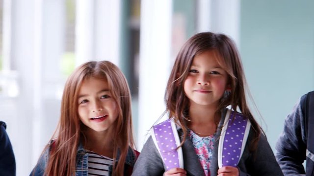 Schoolchildren outside school stand smiling to camera