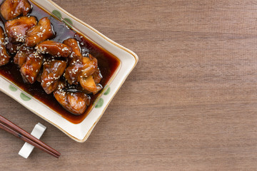 top view of chicken with teriyaki sauce in a ceramic plate on wooden table. delicious and popular japanese food menu.