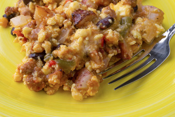 Close view of a scrambled egg burrito meal on a yellow plate with a fork.