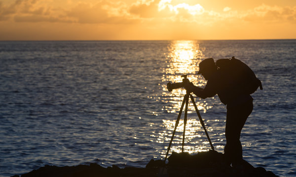 A photographer taking photos at sunset