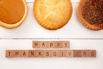 Happy Thanksgiving on a White Wood Table with Various Pies © pamela_d_mcadams