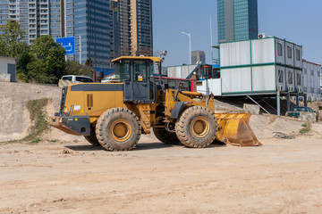 Fototapeta na wymiar industrial building construction site mini bulldozer levelling and moving soil during highway building