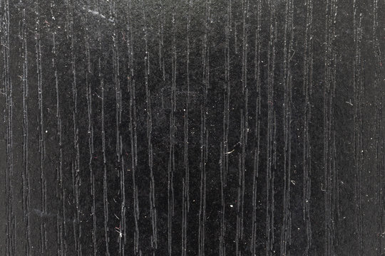 Close view of dust and particles on top of a black desktop.