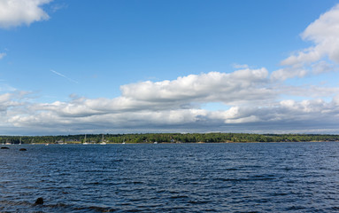Wide view of the boats in Belfast Harbor in Maine on a cloudy summer day with emphasis on the sky.