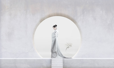 Profile of woman wearing white kimono standing in stone Zen garden