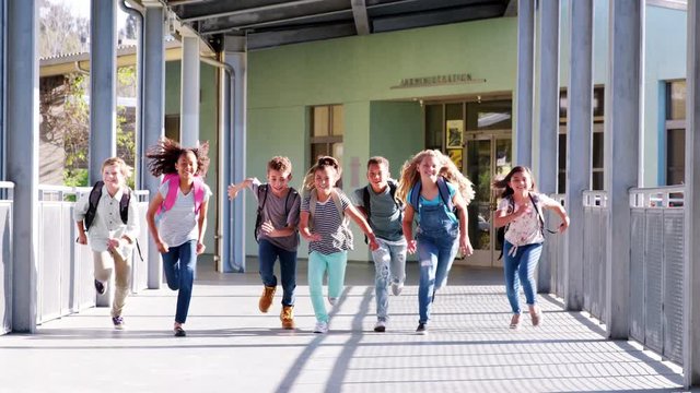 Elementary school kids running to camera in school corridor