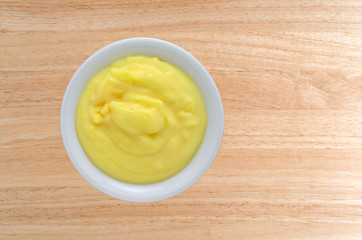 Top view of homemade banana cream pudding in a small bowl atop a wood table.