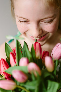 Smiling preteen girl holding a large bouquet of spring tulips.