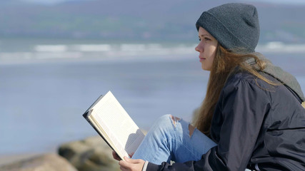 Young woman relaxes while reading a book in the nature