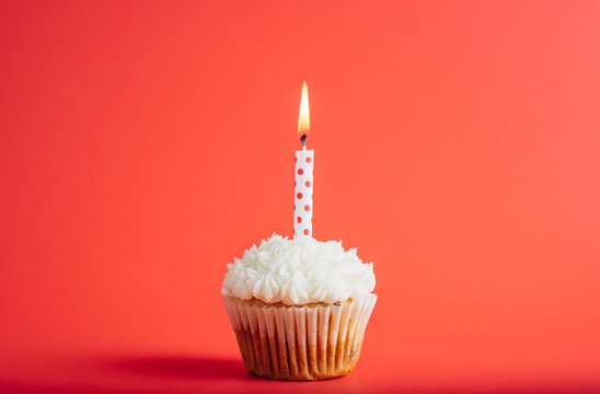 Birthday cupcake with polka dots candle on a red background