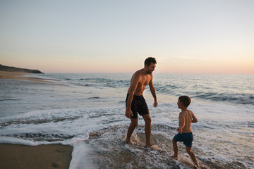 Energetic dad playing with kids on the beach at sunset
